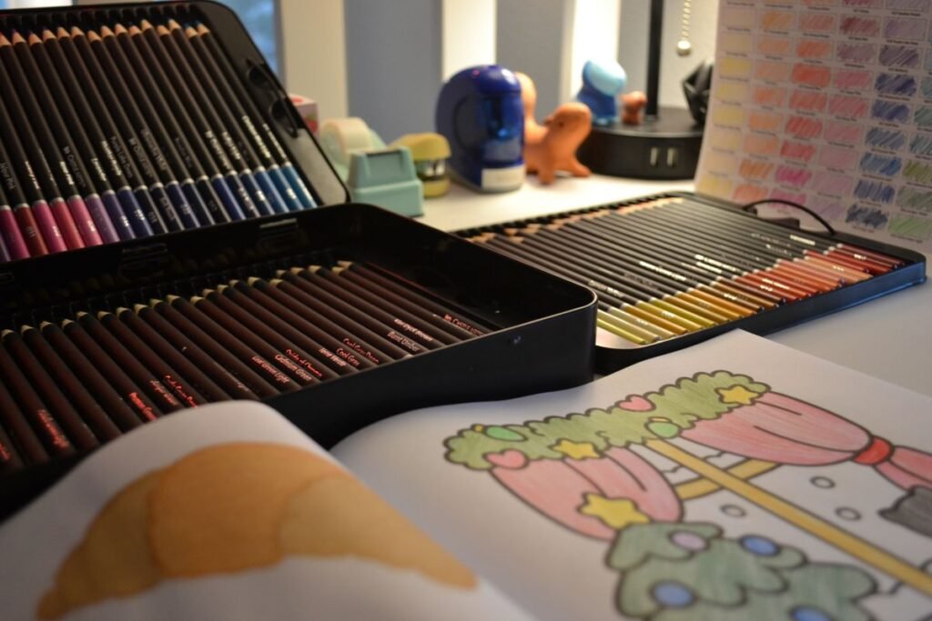 Cahier de coloriage ouvert entouré de crayons de couleur sur un bureau