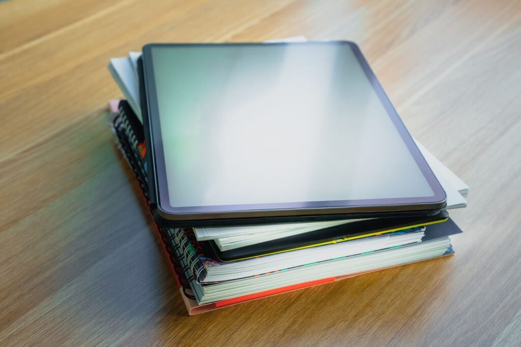 Tablette posée sur une pile de livres, lecture numérique ou papier